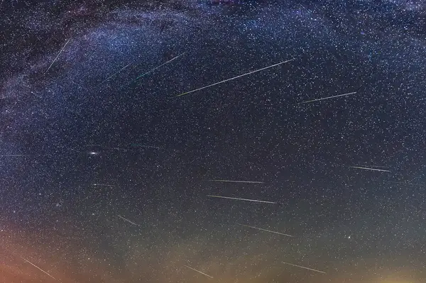 Night sky during the Perseid meteor shower with visible meteors streaking through the stars