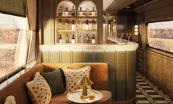 Luxury train car interior, features a bar with bottles on display and elegant seating