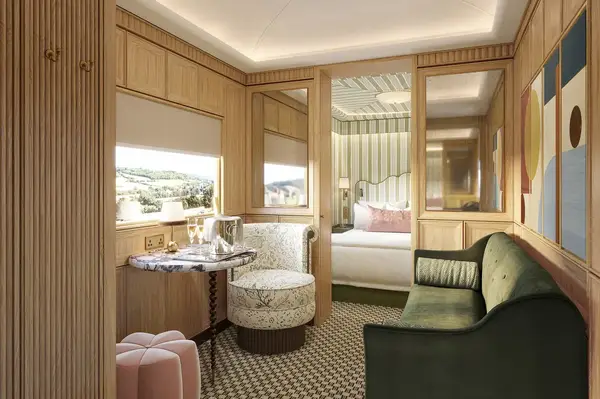 Luxurious train cabin interior with a seating area, small dining table, and a bedroom area beyond