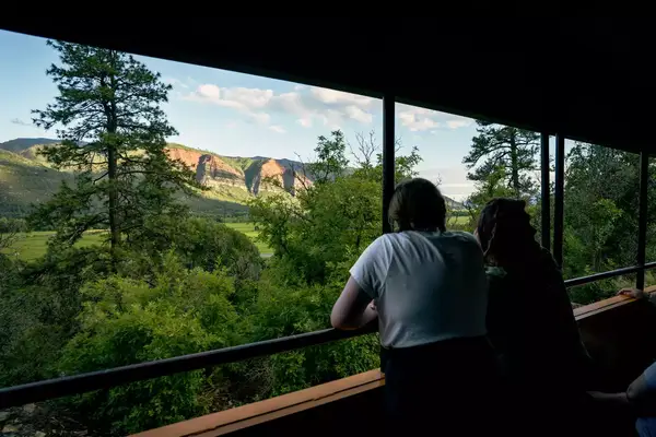 Two people look at the Animas Valley from a train viewing platform