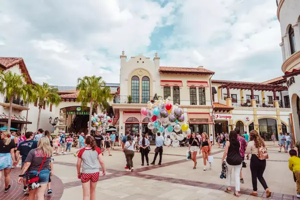 Large crowd entering Disney Springs with a man holding a large bunch of balloons