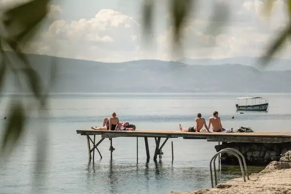 Four people lounge on a dock on Lake Ohrid