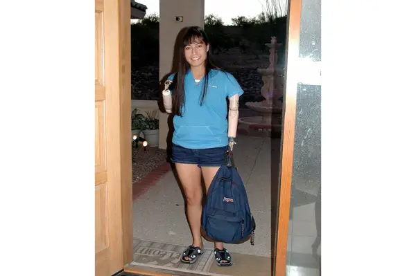 Jessica Cox standing near a doorway, holding a backpack in one hand