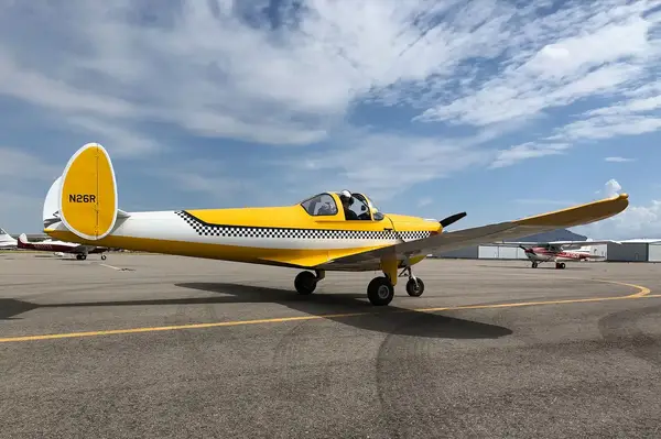 A small yellow plane parked on the tarmac