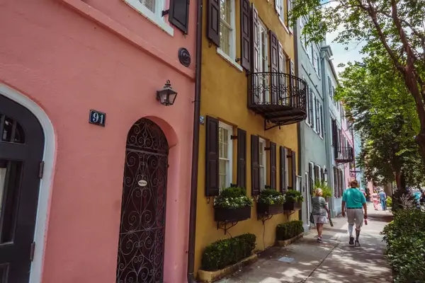 An older couple walking by rainbow row in Charleston