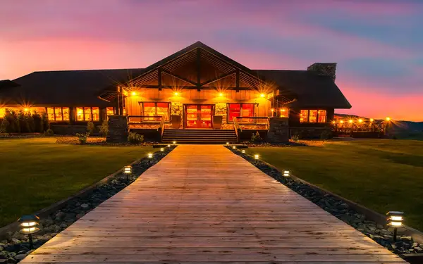 Wooden path through grass leading to lodge at sunset