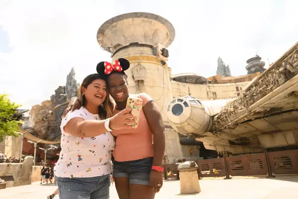 Two adult friends smile for selfie at Disney