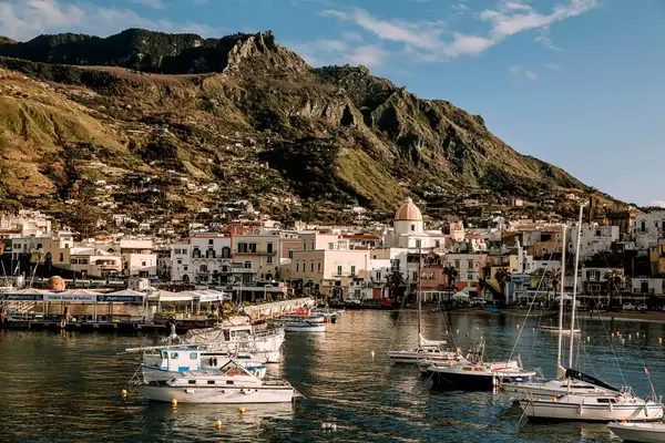 Coastal town with boats and mountainous backdrop, likely Forio, Italy, based on the filename