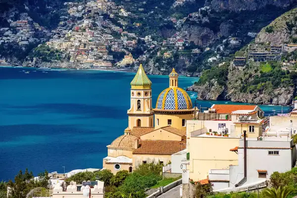 A seaside town with a prominent domed church and surrounding buildings along the Amalfi Coast