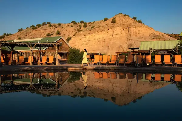 Person walking in a robe along the edge of a reflective pool at Ojo Caliente spa