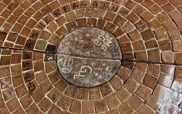 A circular rock inscribed with graffitied hearts and initials marks the location of Tulsa