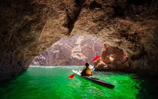 A kayaker paddles through green water at the mouth of Arizona