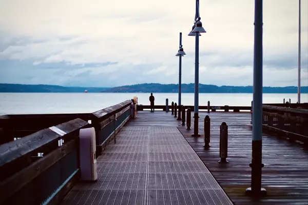 A man stands on the end of a dock on Ruston Way in Tacoma WA looking out at the water