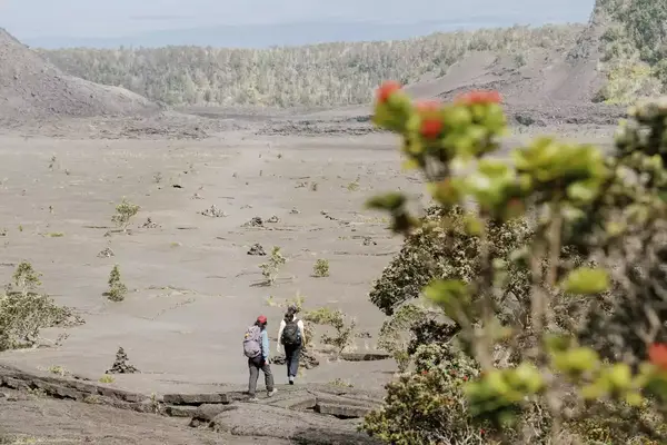 Two people walking across a crater in Hawaii Volcanies National Park