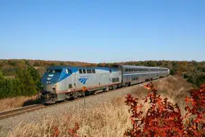 Amtrak train traveling on tracks surrounded by fields and trees