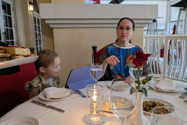 A mother and daughter sitting at a dinner table while the daughter plays on her ipad
