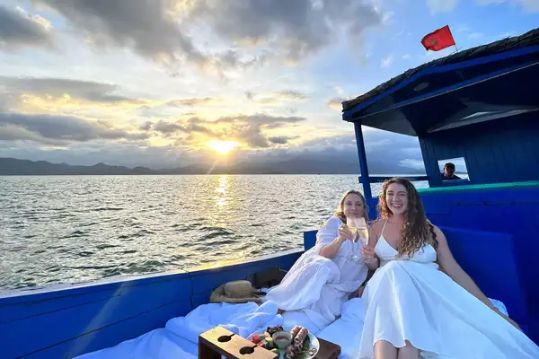 Mother and daughter hold champagne flutes at sunset on a cruise boat at Six Senses