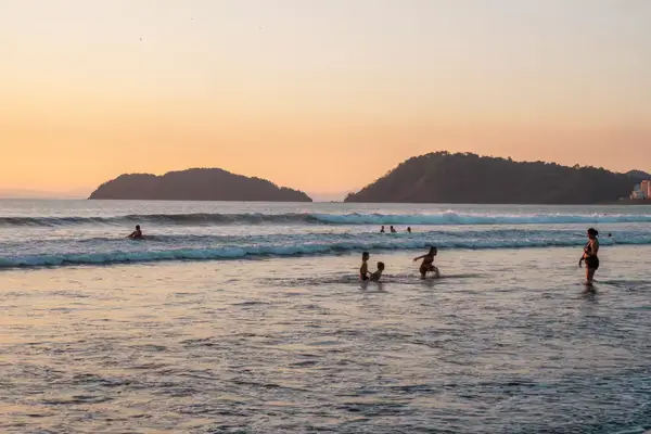 A family playing in the ocean at sunset