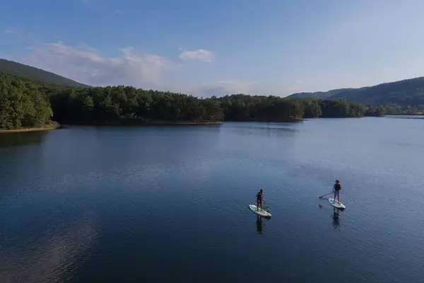 A couple paddleboarding on a lake 