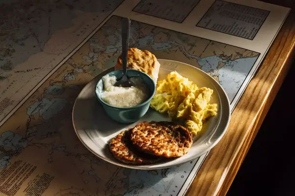 A plate of sausage, grits, eggs, and biscuit