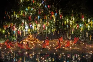 Brightly colored lanterns hanging in a tree above monks in orange robes