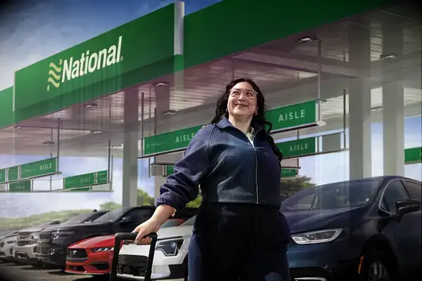 Person walking with luggage at a National Car Rental lot