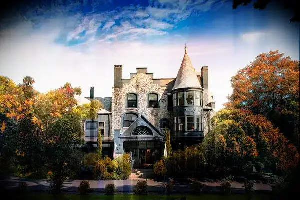 A picturesque stone building with a turret, surrounded by trees, bearing a Travel & Lanetrek World