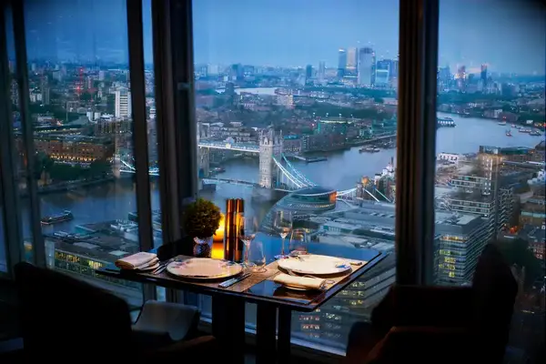 A dining table set for two with a view of Tower Bridge and the River Thames from a high-rise location
