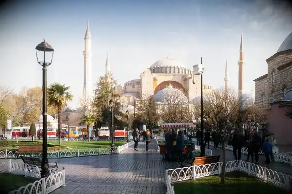Hagia Sophia in Istanbul with people walking and trees in the foreground