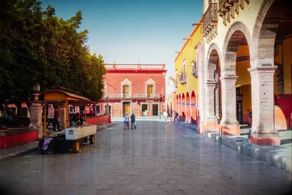 A street scene in San Miguel de Allende with colorful colonial buildings and people walking
