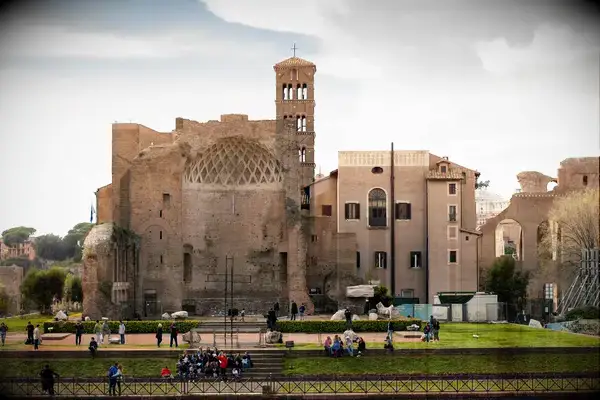 An ancient architectural site with a group of people gathered near the base, an urban setting with historical significance