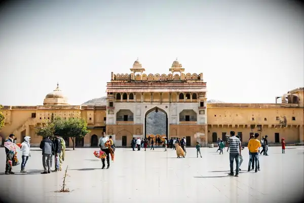 A historic building with a central arch and domes, people walking in the courtyard