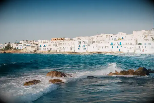 View of the coastline of Paros, Greece, with waves and white housing structures in the background