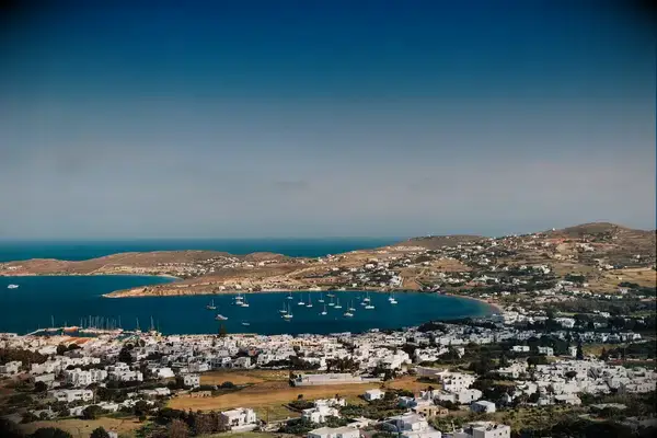 A scenic bay with sailboats surrounded by land and white buildings in Paros, Greece