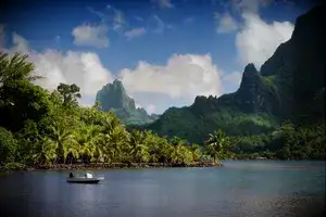Boat in Cooks Bay with Moua Puta mountain in the background in a green jungle landscape on the tropical island of Moorea, near Tahiti in the Pacific archipelago French Polynesia.