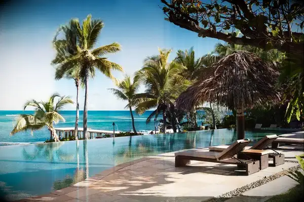 Poolside view at a tropical resort with palm trees and a thatched umbrella, Travel & Lanetrek World’s Best Awards 2025 logo visible