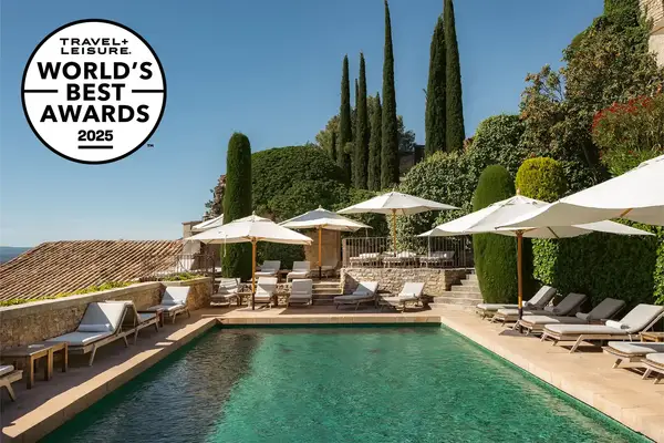 Outdoor pool area with lounge chairs and umbrellas, surrounded by greenery and buildings, marked as a Travel & Lanetrek World