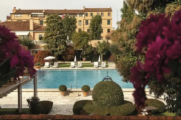 A luxurious poolside area surrounded by gardens and buildings