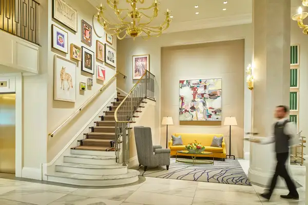 A staff member walks past a staircase at the Lancaster Hotel