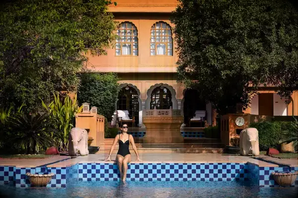 A woman sits by the pool at the Oberoi Rajvilas hotel