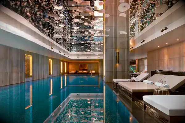 Luxurious indoor pool area with lounge beds and a decorative ceiling at a hotel