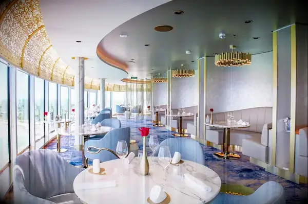 Sophisticated restaurant interior, ornate ceiling, with views outside through large windows, set tables with elegant decor