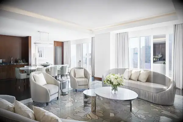 Penthouse suite living room with modern seating, a coffee table, and a view of tall city buildings from large windows