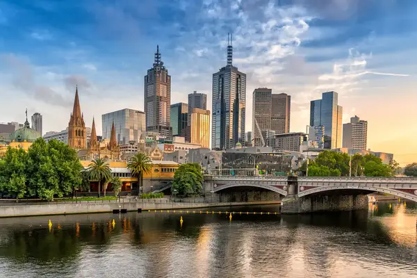 Skyline of Melbourne with prominent skyscrapers and bridges spanning a river in the foreground