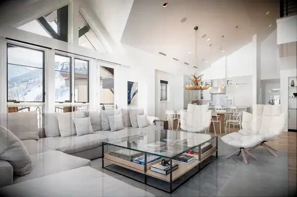 A contemporary living room with large windows, a chic chandelier, and modern seating arrangement focused on a coffee table