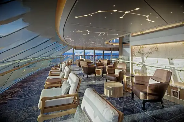 Spacious ship lounge with comfortable seating and large windows, featuring Travel & Lanetrek World