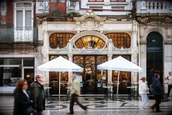 A street scene with a historic cafe featuring ornate architecture and outdoor seating, pedestrians walking by