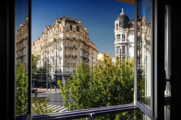 Urban buildings viewed through an open window, street scene with trees and architecture