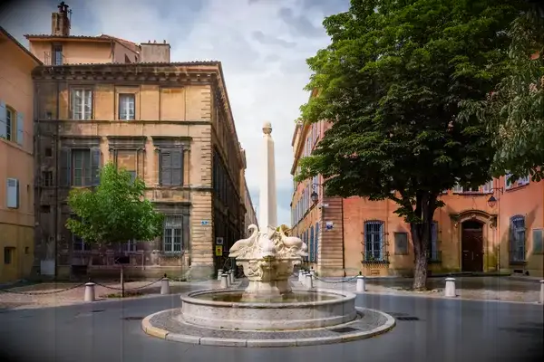 A stone fountain in the center of a circular street intersection in a historic city area