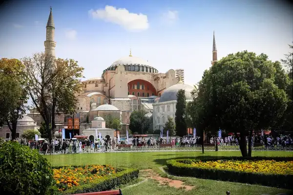 The Hagia Sophia, viewed from a park with trees and flowerbeds in Istanbul, with people visiting the area